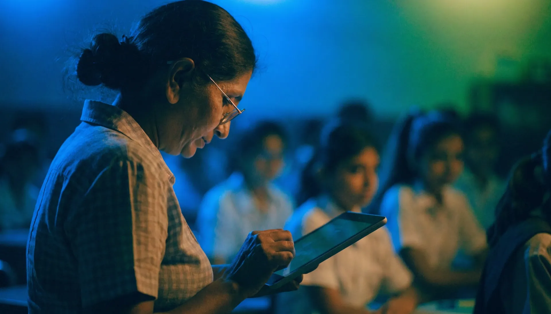 Teacher marking attendance on a tablet in a classroom